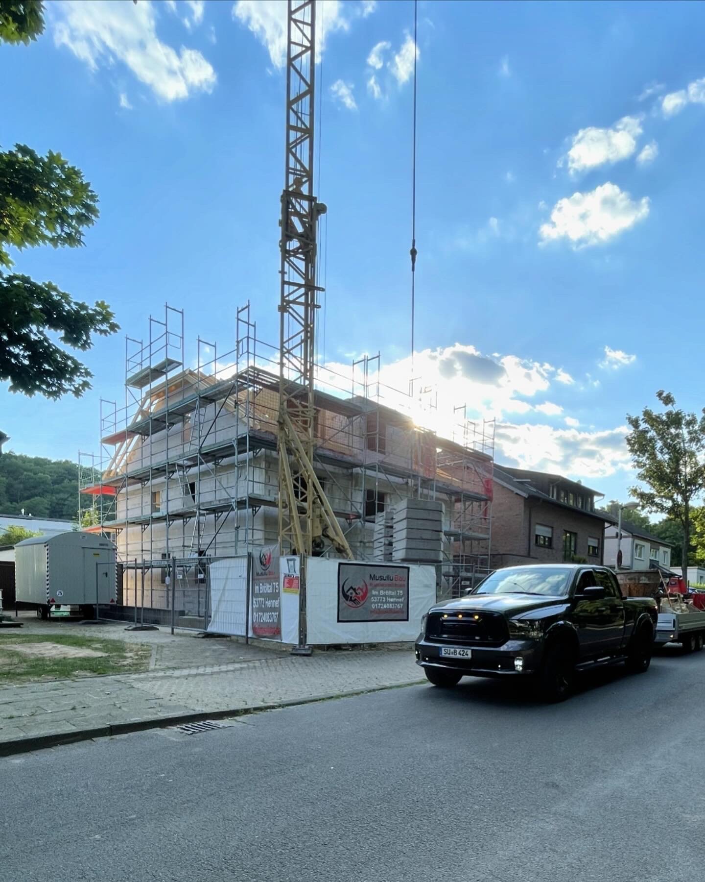 Baustelle Mehrfamilienhaus Straßenseite mit Bauzaun-Banner – Musullu Bau